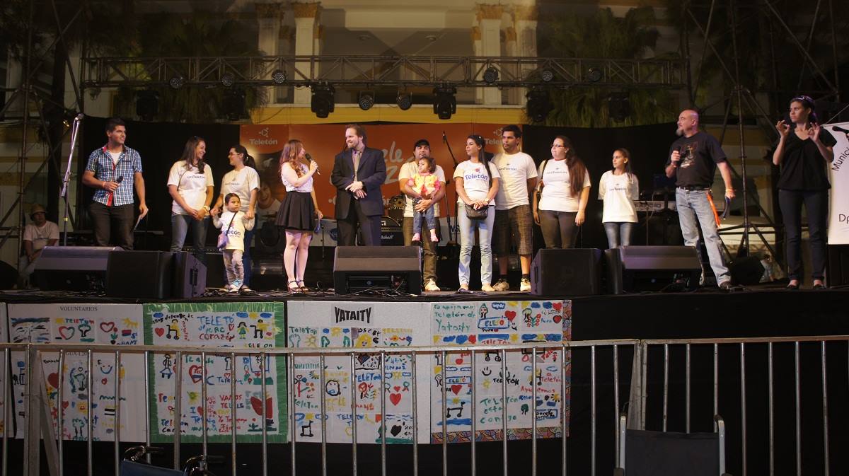 Christian Kaatz on stage at Teletón Villarrica closure night with volunteers, children's artwork, and professional stage setup